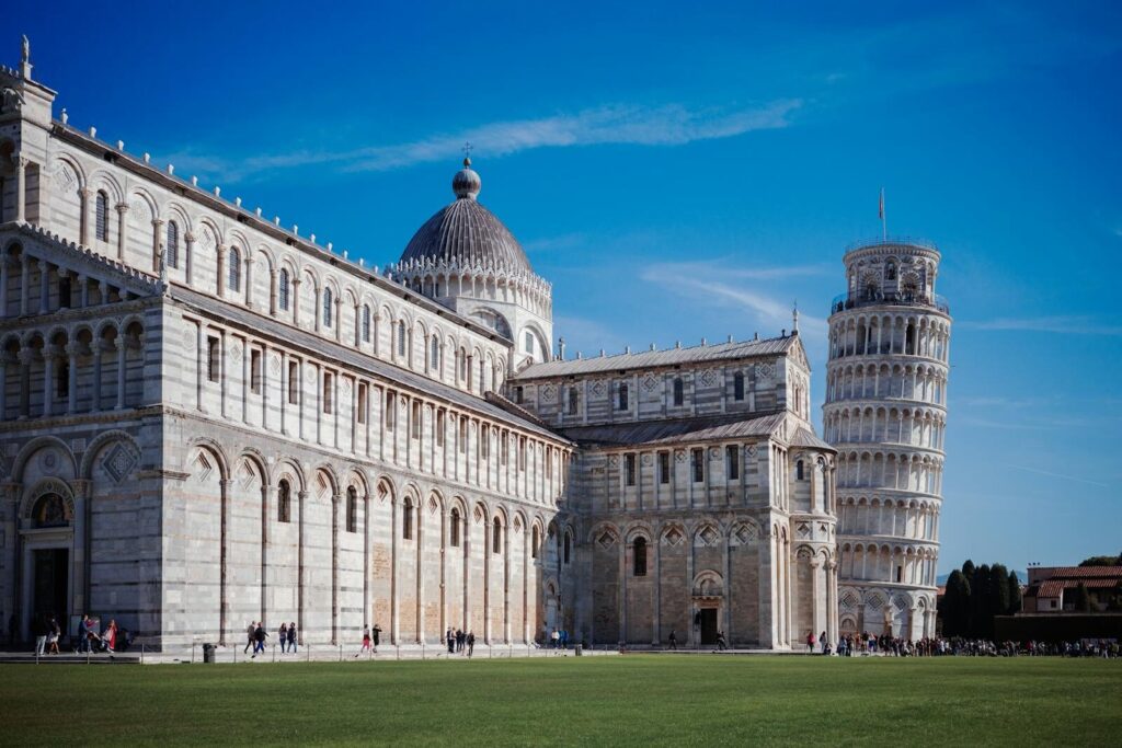 Iconic view of the Leaning Tower and Pisa Cathedral in Tuscany, Italy, on a clear sunny day.