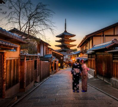 two women in purple and pink kimono standing on street