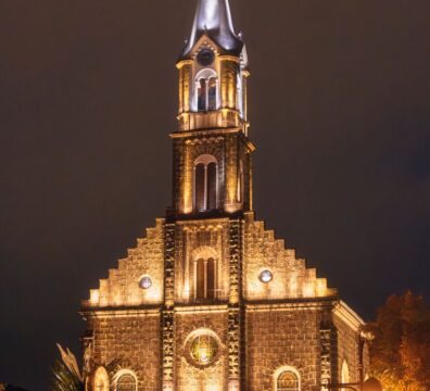 Illuminated facade of Saint Peter's Church in Gramado under a night sky.