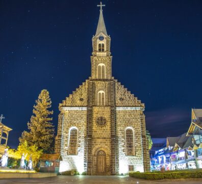 Illuminated facade of Igreja Matriz São Pedro in Gramado, a stunning Gothic-style church under a starry night sky.