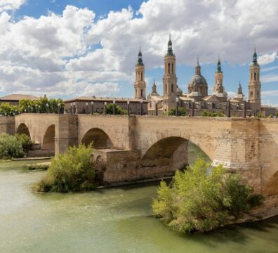Puente de Piedra over a river leading to a large building with towers