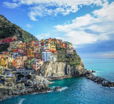 houses on mountain beside sea under blue sky during daytime