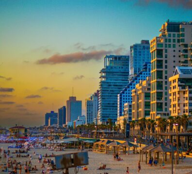 A crowded beach with tall buildings in the background