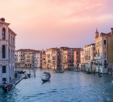 Gondolas on the Grand Canal in Venice under a warm orange sky