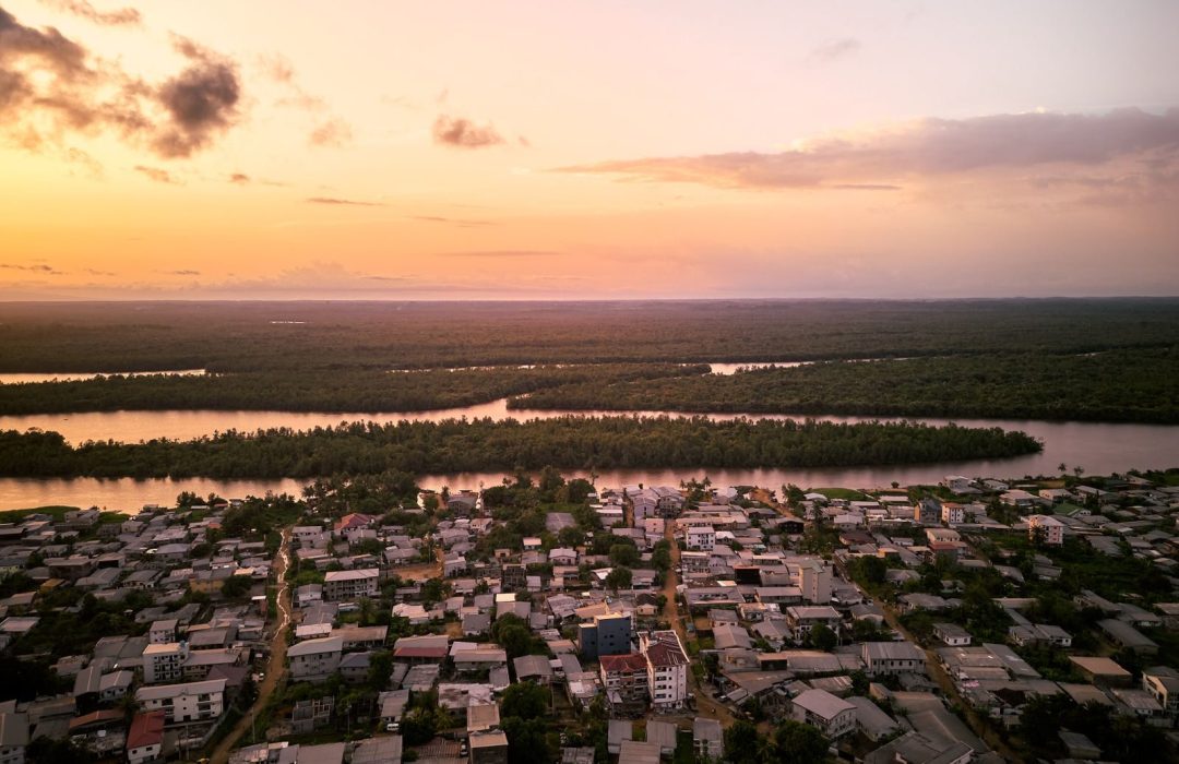 Stunning aerial view of Douala, Cameroon at sunset showcasing the river and urban landscape.