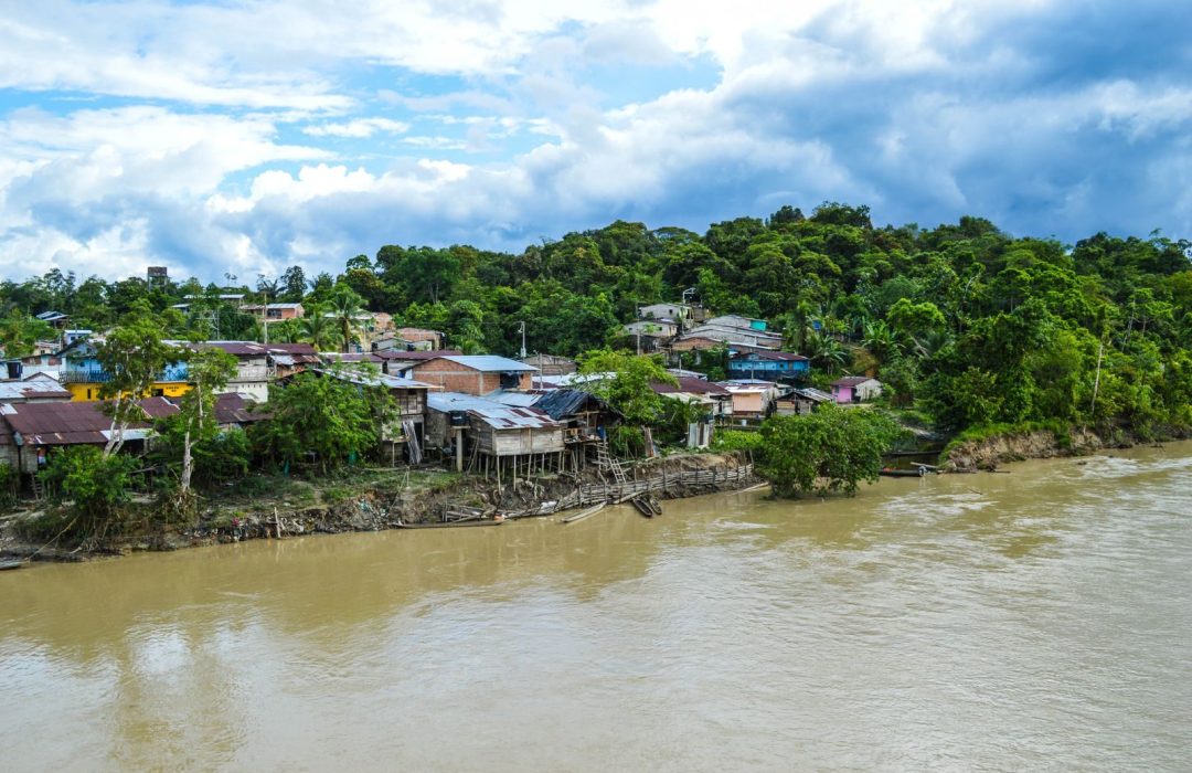 Aerial view of Puerto Nuevo, Chocó, Colombia, with lush greenery and riverside houses.