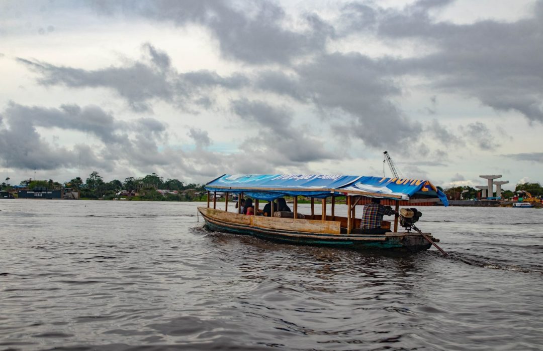 Explore the Amazon River near Iquitos, Peru, with local transportation amidst a cloudy sky.